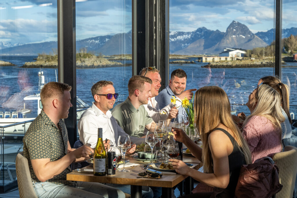 Dining with a View at Ringstad Resort Group of guests dining together indoors with sea and mountain views at Ringstad Resort