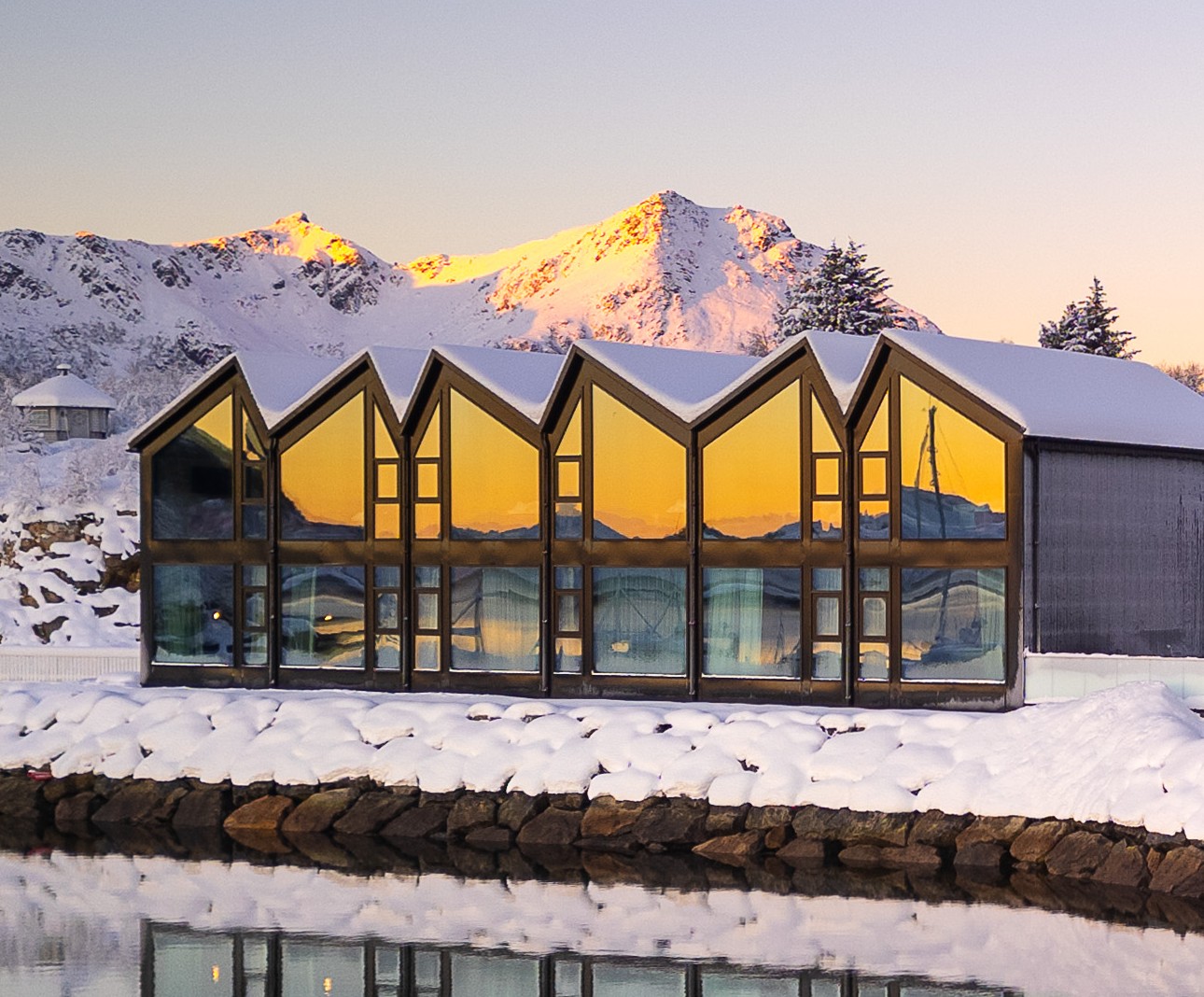 Panoramic glass building at Ringstad Resort with snow and mountain reflections