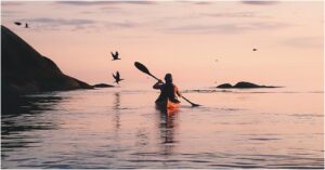 Guest kayaking at sunset along the Arctic coastline at Ringstad Resort