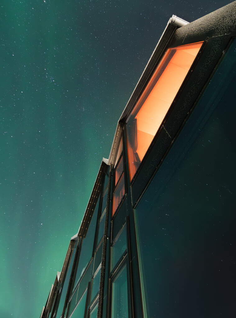 Northern lights above modern oceanfront suites in Arctic Norway